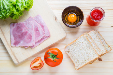 slices of bread with jam and ham, tamoto, lettuce, egg on table with kitchen on table with kitchen