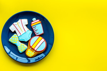 Cook gingerbread cookies on plate for baby shower on yellow colorful background top view mockup