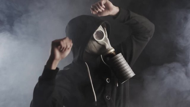 man in a gas mask in smoke in a dark room