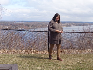 Professional looking mid-aged Filipina lady walking through a fenced park above a large lak.

