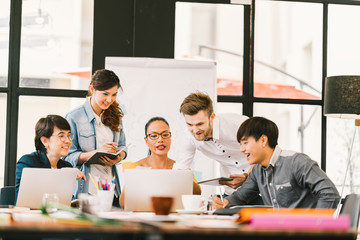 Multiethnic team busy discussion using laptop, digital tablet. Coworker partnership, college student meeting. Small business casual office, freelance designer job, or online marketing analysis concept