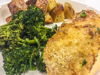 Breaded and herbed chicken breast fillet served with broccoli and potatoes