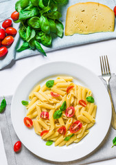 Colorful penne rigate pasta dish with cherry tomatoes and basil leaves