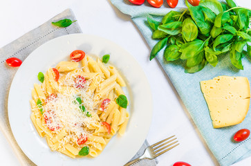 Colorful penne rigate pasta dish with cherry tomatoes and basil leaves and cheese