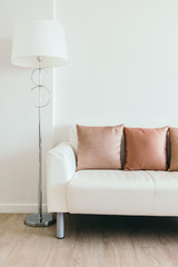 Comfortable pillow on white sofa with light lamp