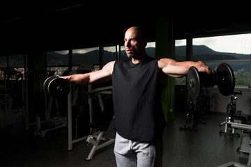 Fototapeta na wymiar Shoulders Exercise With Dumbbells In A Gym