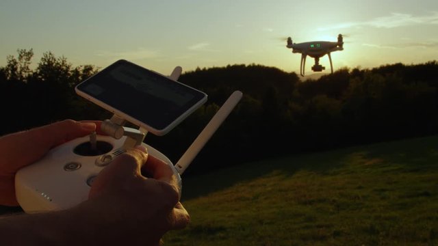 SLOW MOTION CLOSE UP: Man's hands flying quadro drone with modern white RC transmitter. Unrecognizable person controlling drone over RC radio controller. Man flying and filming with drone camera