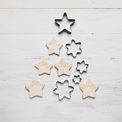 Christmas tree from cookies and different metal shapes on a white wooden background. A traditional symbol of Christmas. The festive concept.