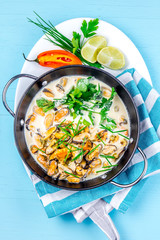 Mussels in creamy milk sauce with aromatic herbs and lemon. Top view Blue background. Top view