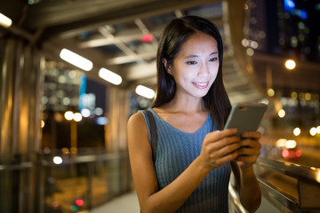 Woman sending sms on smart phone at night