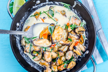 Mussels in creamy milk sauce with aromatic herbs and lemon. Top view Blue background. Top view