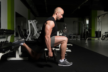 Fototapeta na wymiar Man Exercising Legs With Dumbbells In The Gym