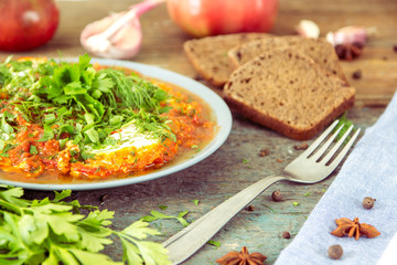 Shakshuka - jewish traditional recipe. Breakfast with fried eggs, tomato sause, pepper and green