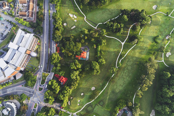 Aerial view. A golf course just beside the road and buildings.