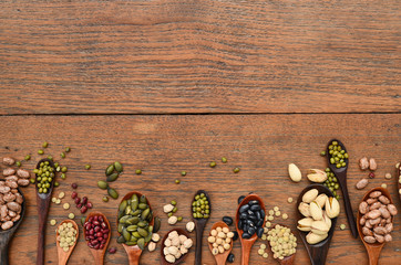 Assortment of beans and lentils in wooden spoon on teak wood background