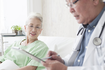 Obraz premium An old doctor is talking to an elderly patient while watching a medical record