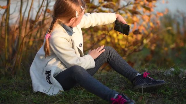 A young girl makes a selfie in the autumn forest