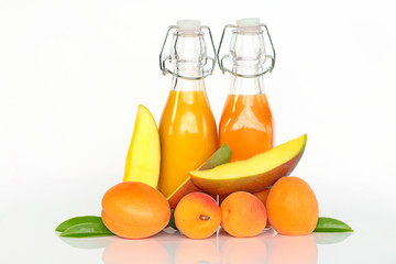 Smoothies of apricots and mangoes. Orange and yellow smoothies in glass bottles, a slice of mango and fresh apricots on a white background. Super food and organic dietary vegan food concept