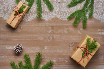 Christmas background gift in Kraft paper tied with twine adorned with spruce branch, lace on  old boards and cedar cones