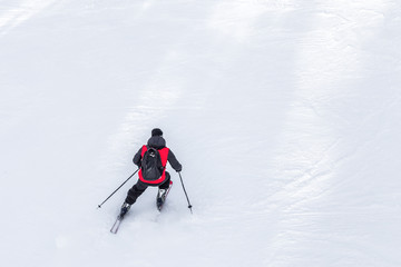 Fototapeta na wymiar Man skier with red coat and black backpack skiing on fresh white snow on ski slope on Sunny winter day with Copy space in uludag mountain Bursa,Turkey.