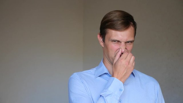 4k. Slow motion. Close up portrait of a young man. body language and gestures. he is disgusted and closes her nose. smell