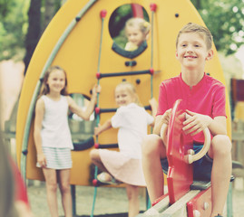 Fototapeta na wymiar Smiling boy sitting on swing on children's playground