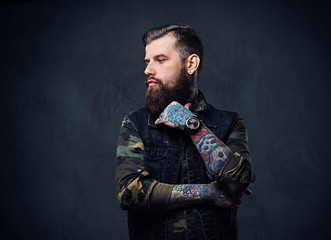Portrait of bearded tattooed hipster male dressed in a military jacket.