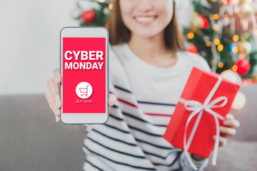 Young beautiful Asian Woman hands holding gift box and smartphone with cyber Monday screen.Smile...