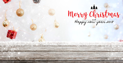 Fototapeta na wymiar Wood table top on blur with bokeh christmas tree background with snowfall and Merry Christmas & Happy New Year 2018 sign - can be used for display or montage your products.