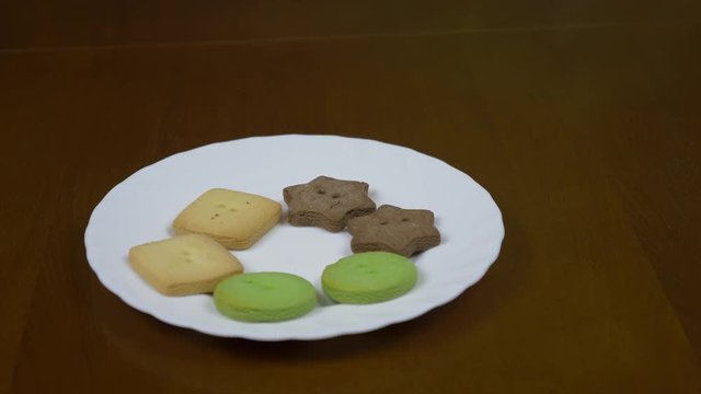Close up top view of plate with cookies on dark brown table. Plate with bisquits track panning LR RL. Slider shot.