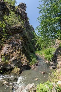 Stream at the bottom of a gorge at the Divoka Sarka on a sunny day. It's a nature reserve on the outskirts of Prague in Czech Republic.