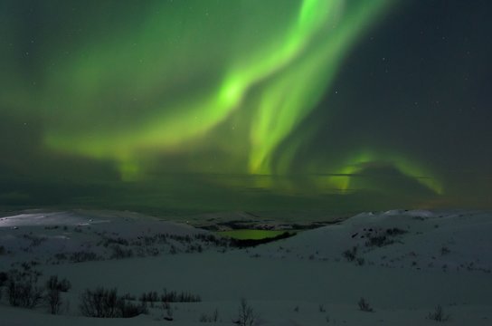 Hills and tundra covered with snow and in the sky the stars, the Aurora.