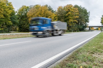 Fototapeta na wymiar Vorbeifahrender Lastwagen auf einer Landstraße, Deutschland