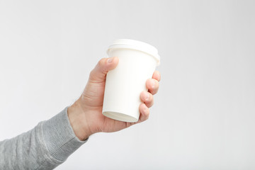 A paper cup of coffee in the hand. White paper cup of coffee in hand. For mock up. Isolated.