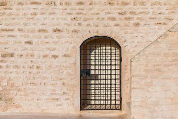 A metal lattice in front of the gates set in a sandstone wall of the fort