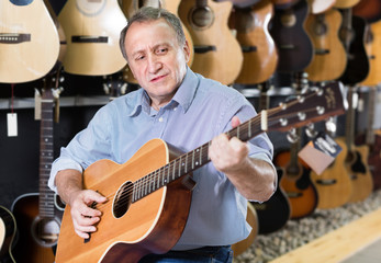 Naklejka premium Adult man is playing on wooden acoustic guitar