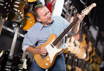 Happy man is playing on wooden electric guitar