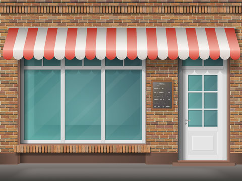 Cafe or store front with large transparent window and awning. Facade of red brick. Empty glass showcase of boutique. Entrance in the small  shop.