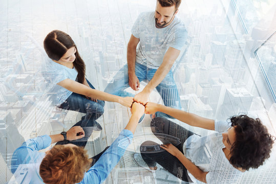 Pleasant coworkers keeping fists together