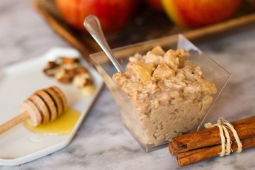 Oatmeal porridge snack with apples, cinnamon, nuts and honey on marble surface