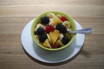 Fruit and berry salad (oranges, blackberries, raspberries, bananas) in a green dish.