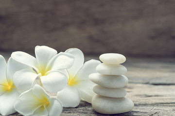 Pile of white zen stones and Frangipani flower  on rustic wood background,retro effect