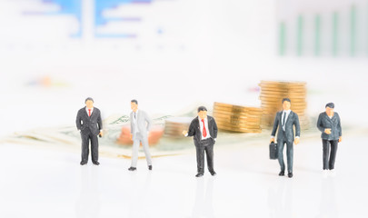 Miniture success businessman team work meeting with coins and graph chart background