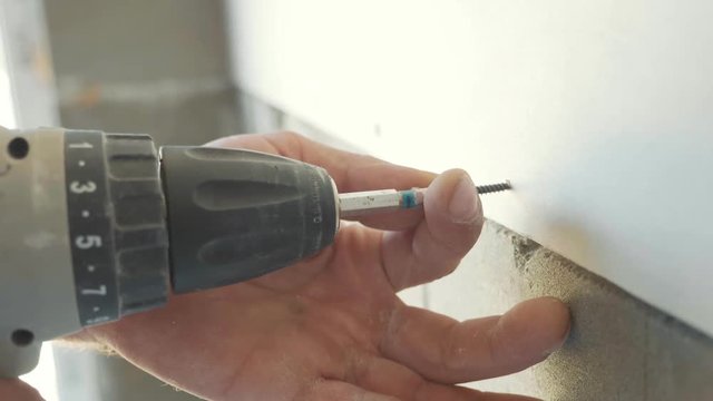 Worker make install drywall and using screwdriver and screw for work, closeup