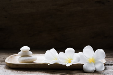Obraz na płótnie Canvas Beautiful plumeria or temple,spa flower with white zen stones on rustic wood background
