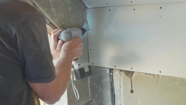 Worker make install drywall and using screwdriver and screw for work, closeup