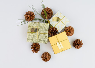 Christmas ornament golden gift boxes set and pine cones fresh green branch on white background,flat lay