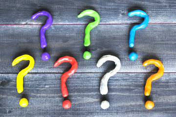 Colorful plasticine question marks on the dark background, asking question and finding solution...