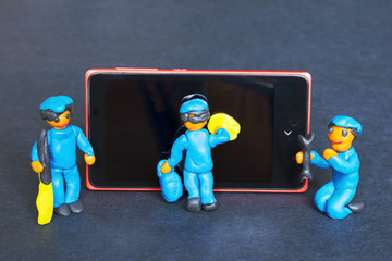 Obraz premium Plasticine people cleaning and repairing a mobile phone.