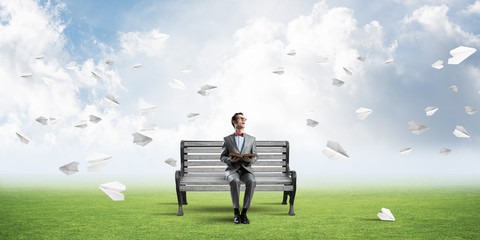 Young businessman or student studying the science and paper planes fly around